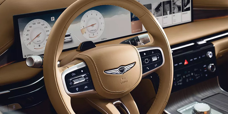 Close-up of the luxurious interior of a car featuring a sleek steering wheel and advanced digital displays.